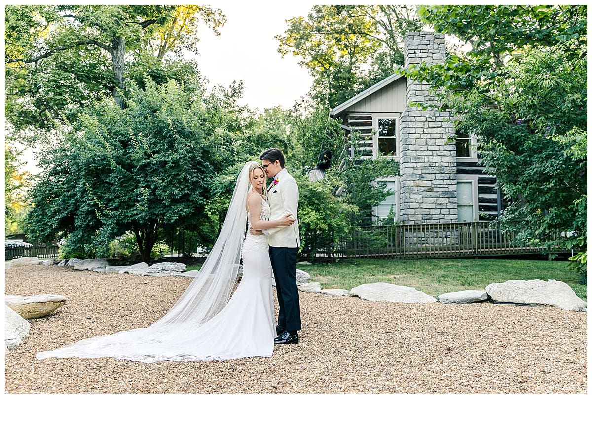 bride and groom in an embrace in front of historic log home
