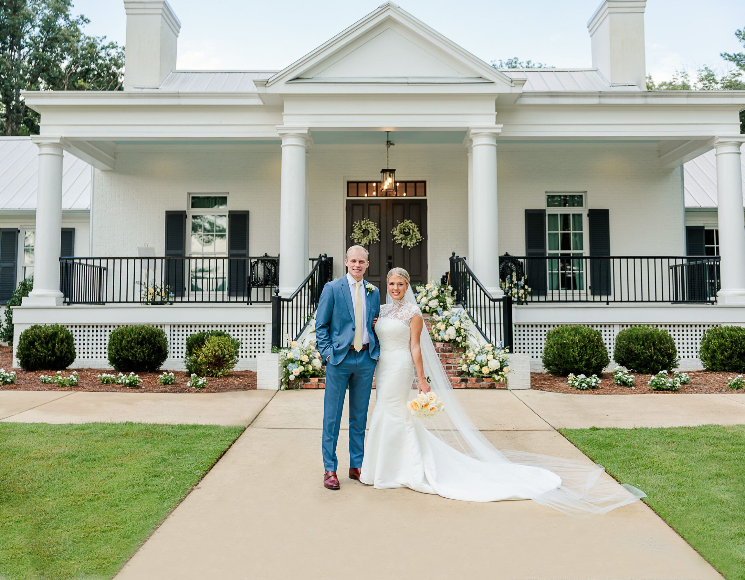 bride and groom in front of a stately southern home