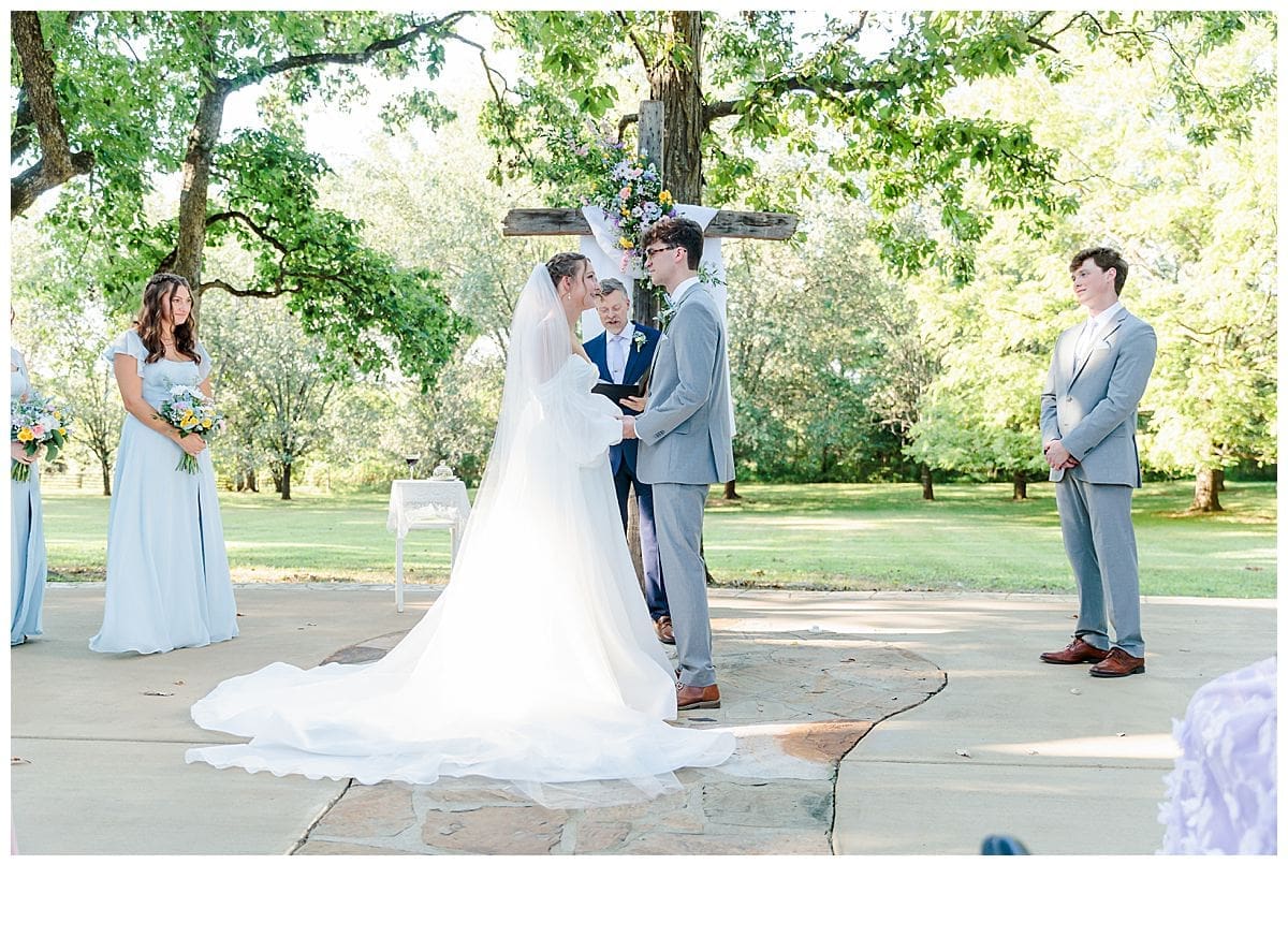 Bride and groom standing at the cross exchanging vows during their wedding ceremony