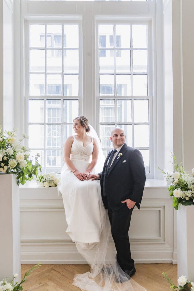 Bride and groom portraits with bride sitting in the window seal in the Sadee gallery of the Noelle Hotel