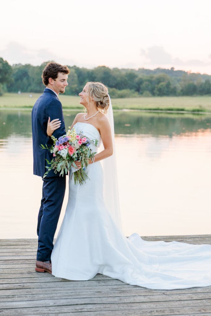 Bride and groom in golden hour light on a dock on a pond.