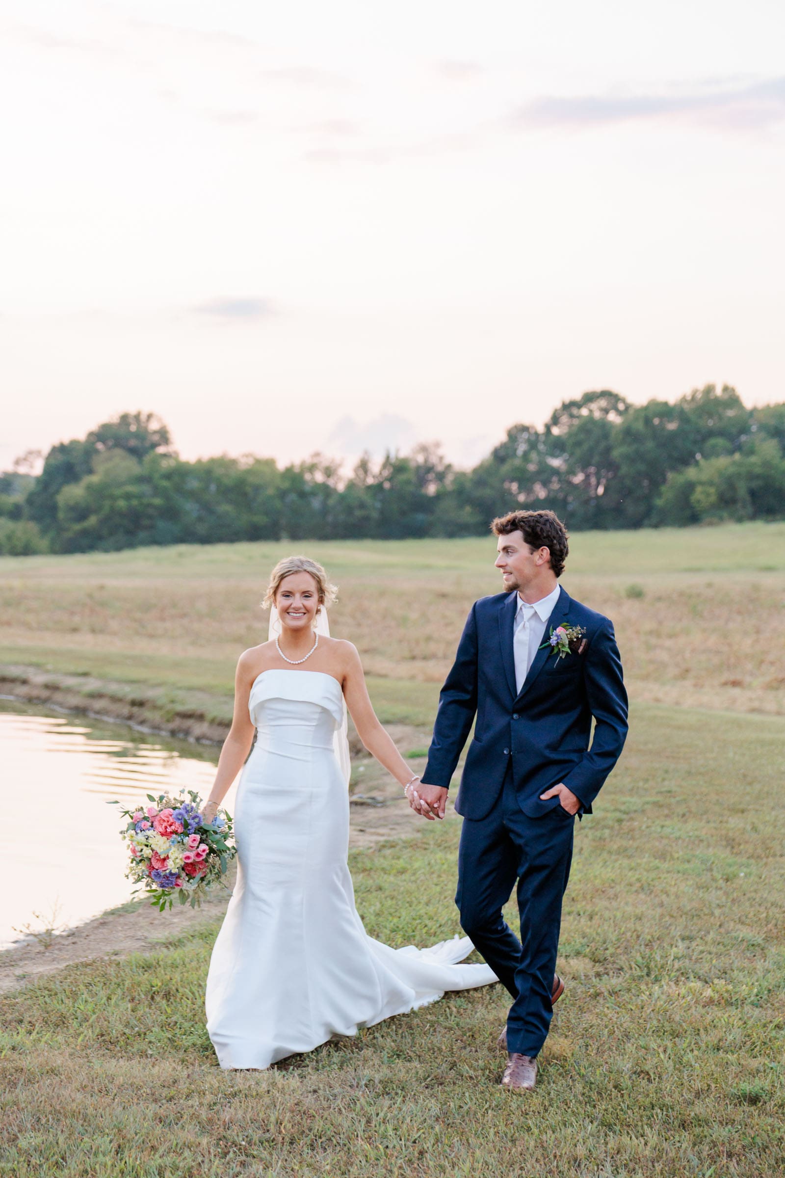 Bride and groom walking hand in hand in the golden hour light.