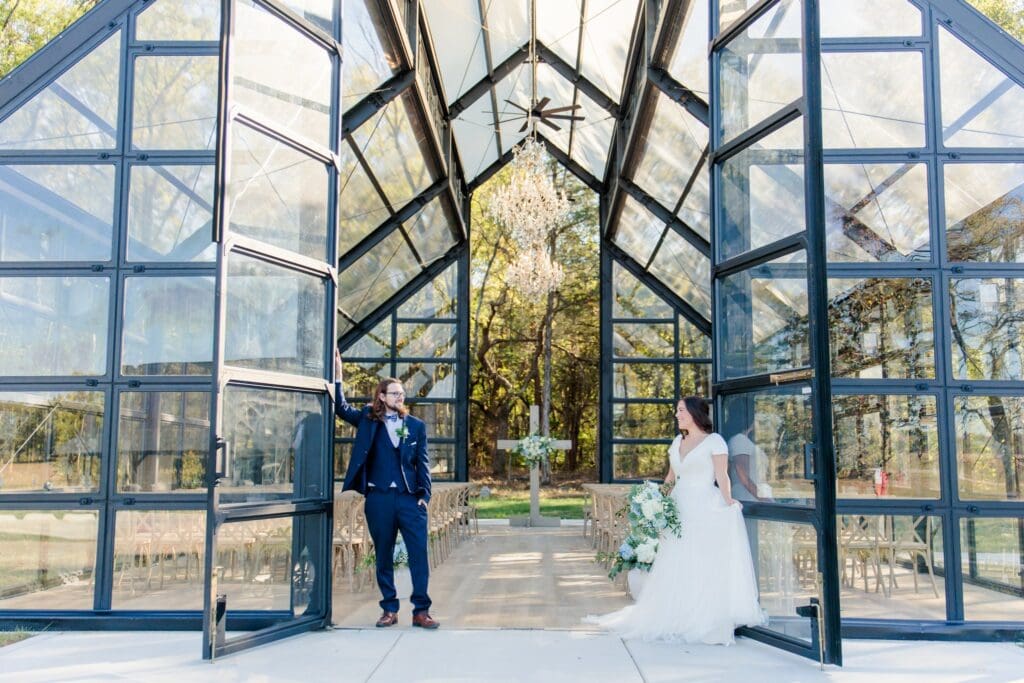 Bride and Groom posing at glass chapel at Jubilee Woods