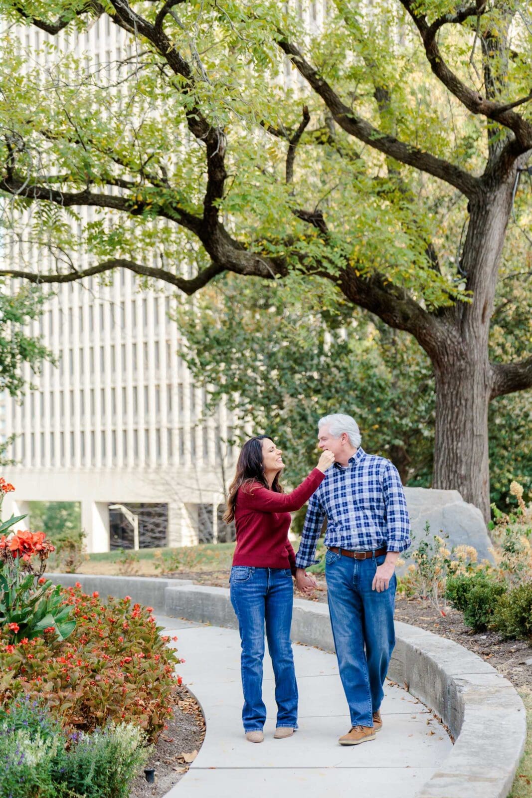 Sarah and Michael walking beneath the trees in a Nashville park