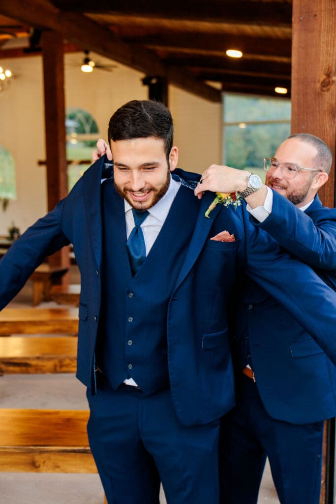 groom getting dressed with the help of his best man.