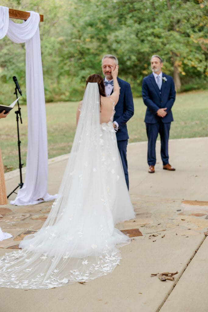 Bride wiping tear from groom's eye during their Iriswoods wedding ceremony