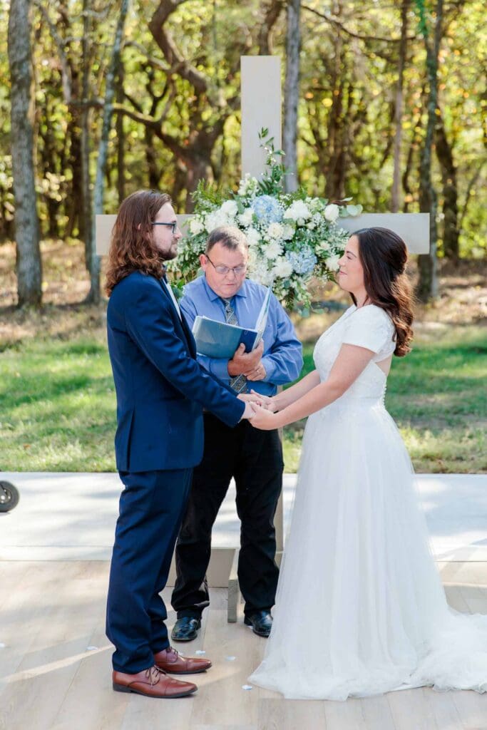 Macy and Logan exchanging vows inside the glass chapel at Jubilee Woods