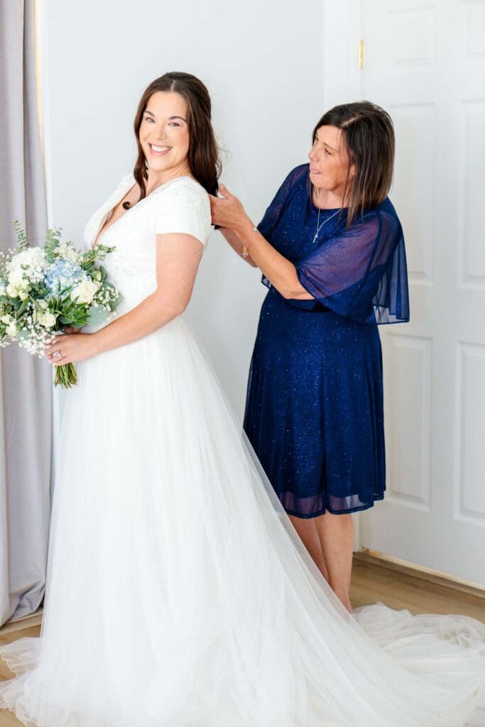 Mother helping the bride into her wedding dress at Jubilee Woods