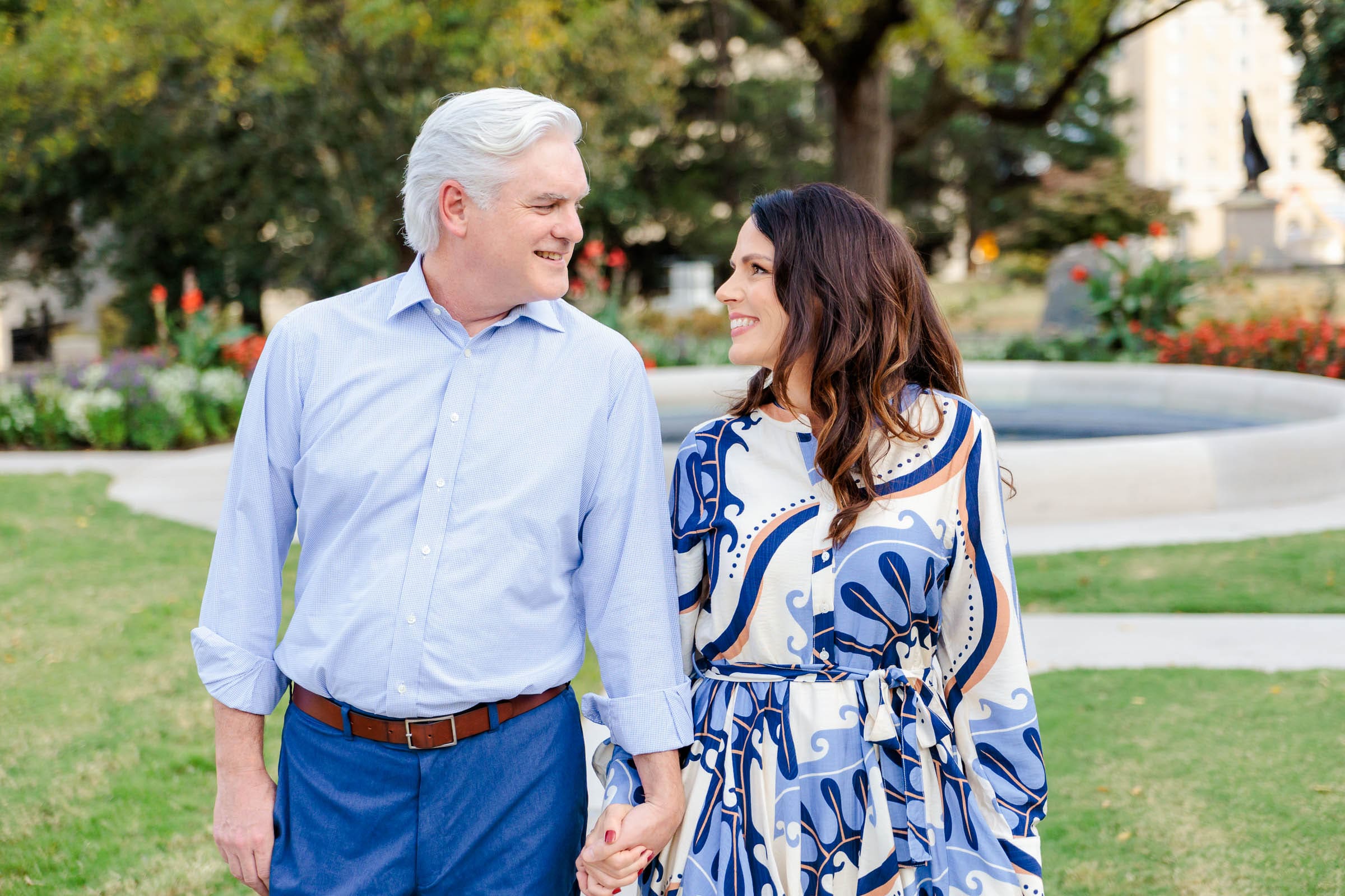 A couple walking hand in hand looking at one another in a park
